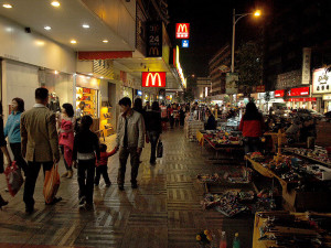 Straßenszene in der chinesischen Stadt Kaiping, die gleichzeitig einen kantonesischen Dialekt bezeichnet; in diesem ist das Gedicht 'Moon Rhyme' verfasst, zu dem Caroline Szeto ein Klavierstück komponierte (Xijiao Road, Kounoso, GNU Free Doc. Lic.).